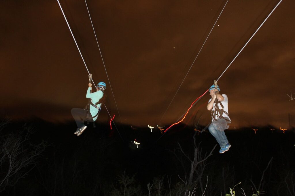 Coral Crater’s Night Zipline Adventure with two people ziplining in the dark.
