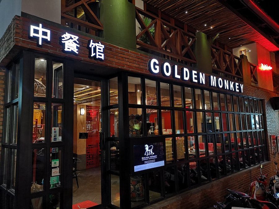 Exterior of Golden Monkey Ubud at night, with glowing signs and large windows revealing the red interior.