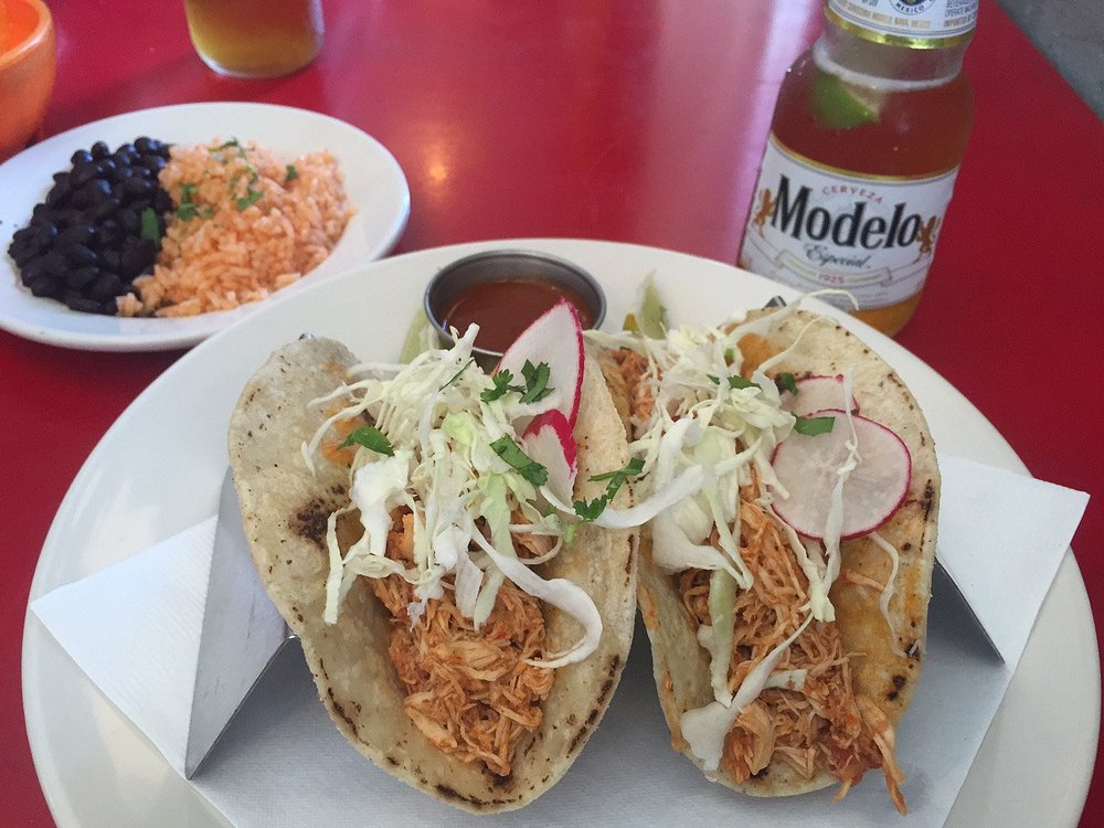 A plate of shredded chicken tacos at Gringo A Go Go, served with black beans, rice, and a cold Modelo.