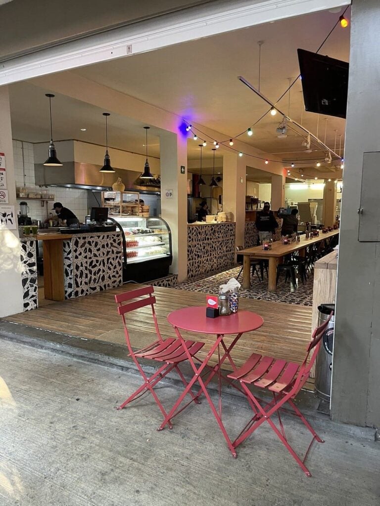 Outdoor seating at Lalo! with a view into the casual, cozy restaurant interior.