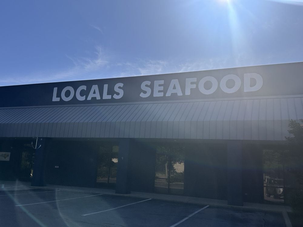 The exterior of Locals Seafood with bold white lettering and a sunlit, empty parking lot.