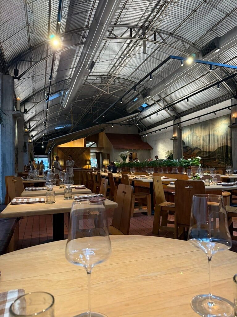 Spacious dining room at Máximo with wooden tables and an industrial ceiling.