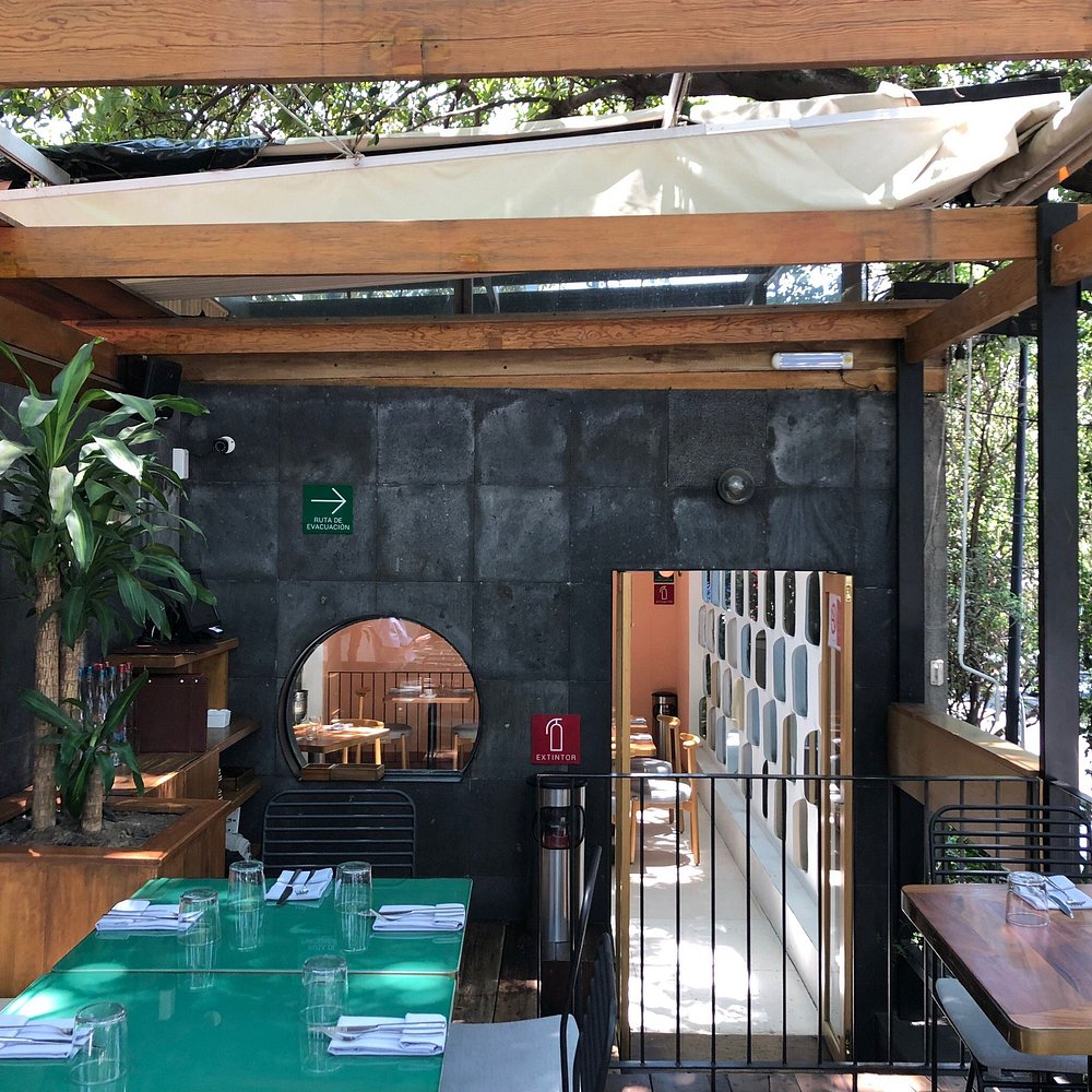 Modern, open-air dining area at Meroma with wood and concrete elements.