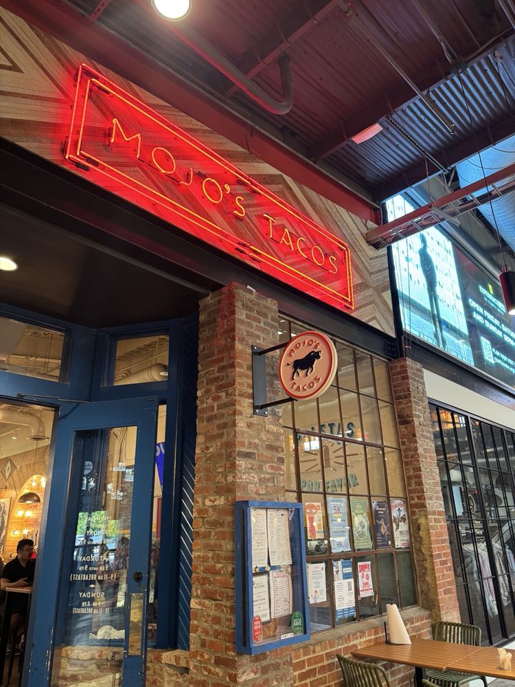 Neon-lit exterior of Mojo's Tacos – Franklin with brick walls and a bright red sign.