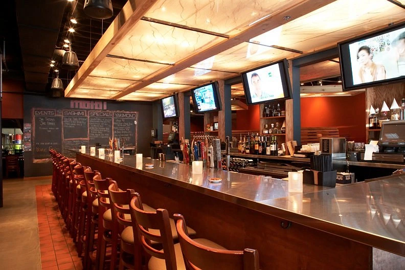 Moto-i Minneapolis sake brewery bar interior with wooden stools and craft sake taps at night