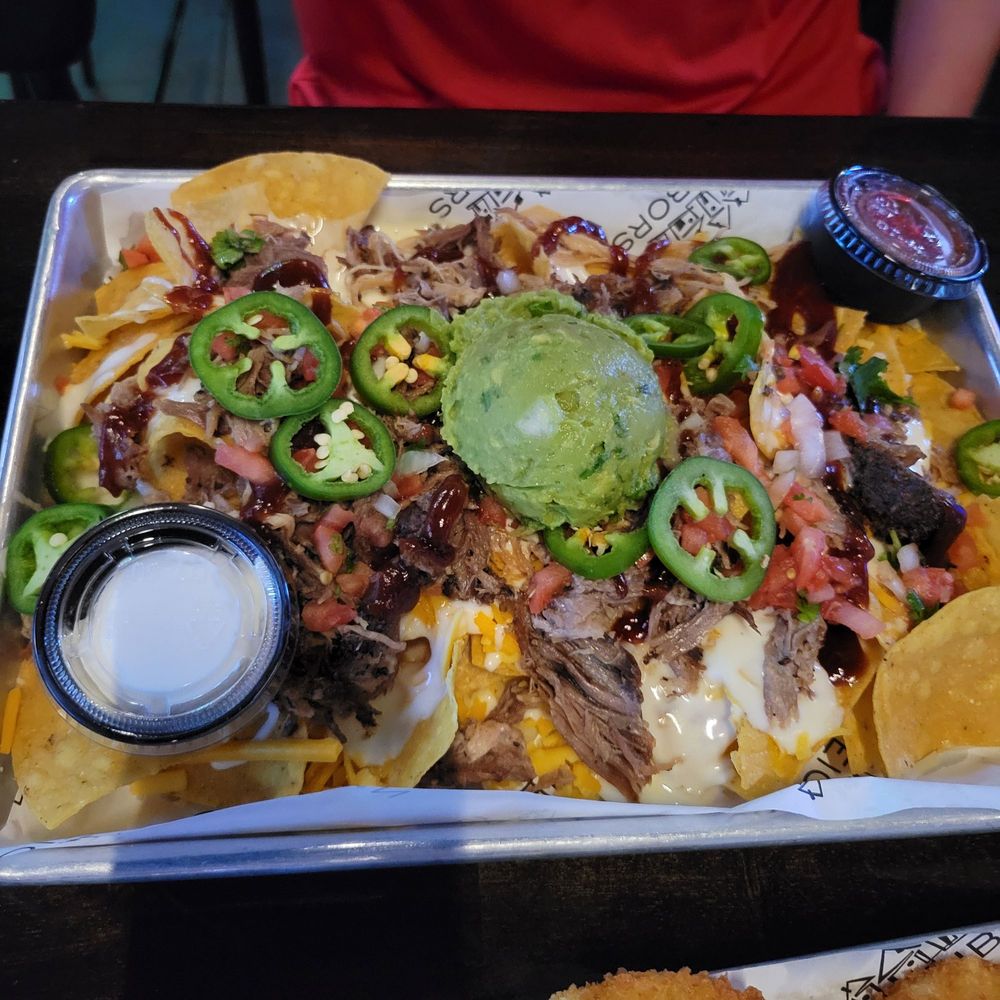 Tray of loaded nachos topped with guacamole, jalapeños, and pulled pork at Neighbors of Franklin.