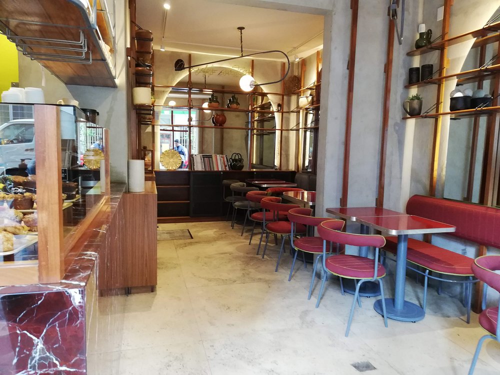 Cozy interior of Niddo with red seating and a visible pastry counter.