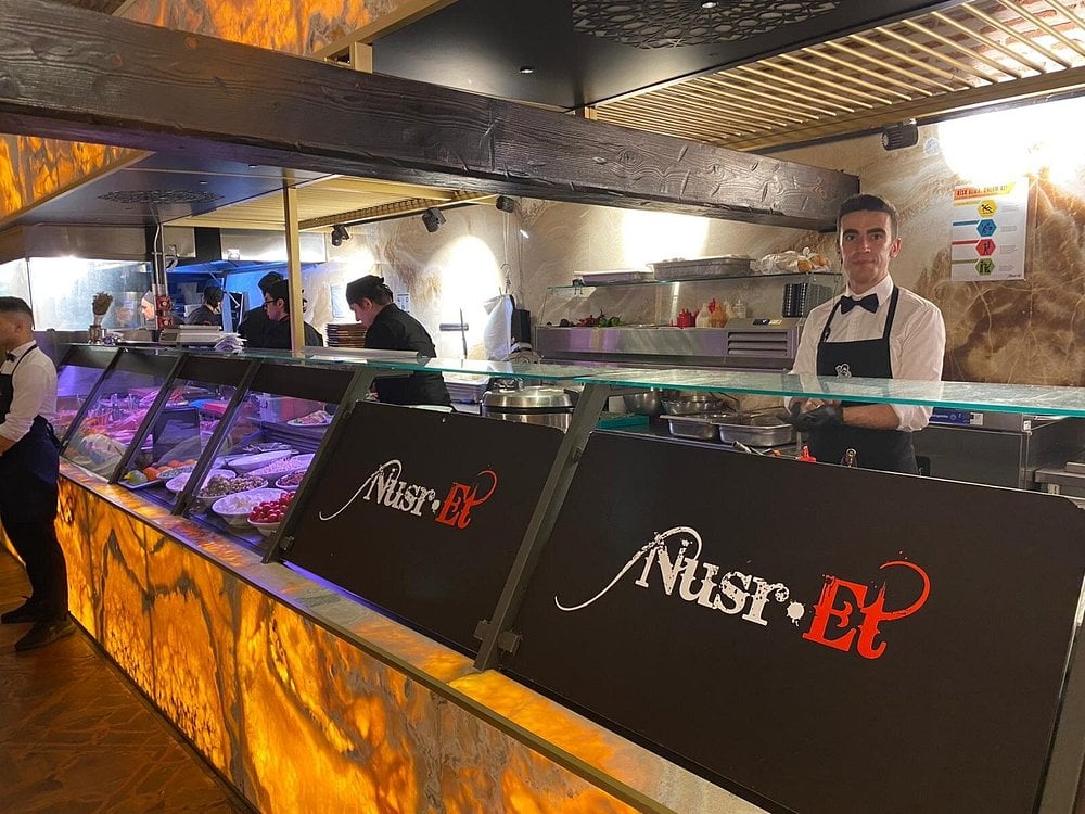Staff behind the counter at Nusr-Et Steakhouse showcasing meats