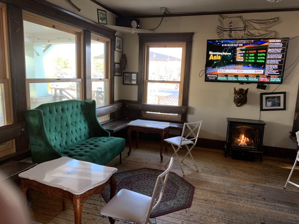 Homey lounge area inside Pignic Pub & Patio with a green velvet couch and fireplace.