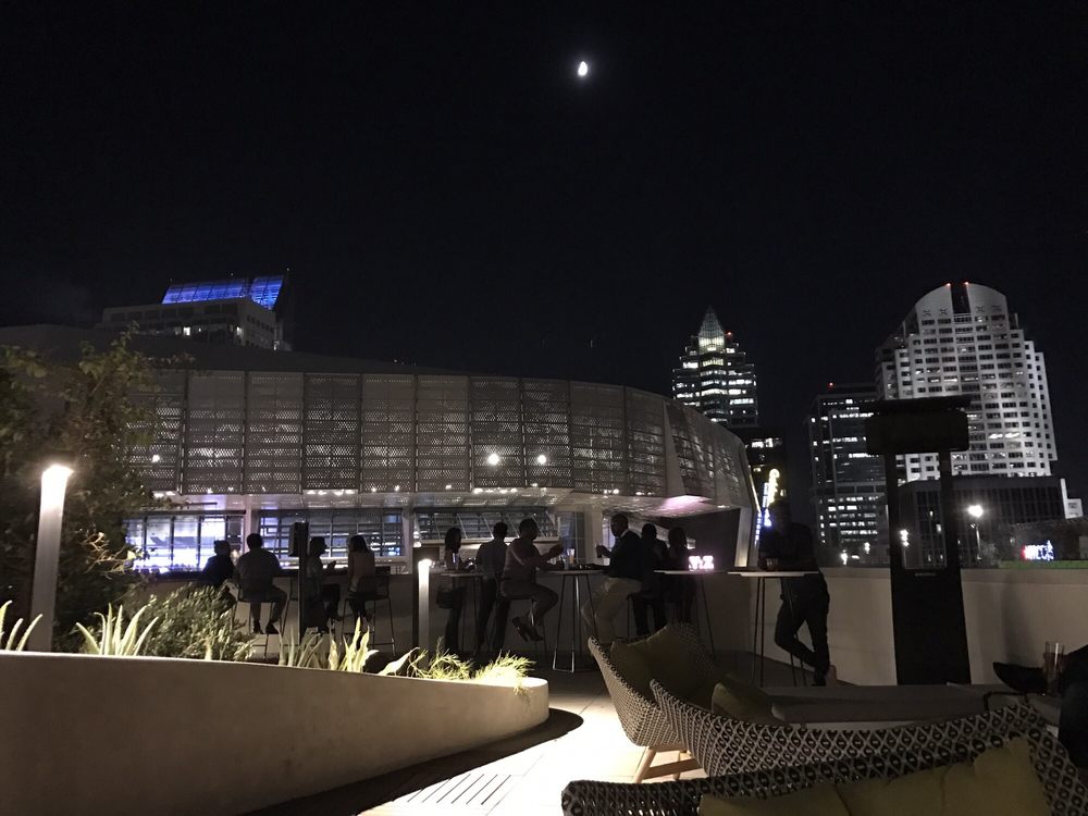 Rooftop bar at Revival with city skyline views at night.
