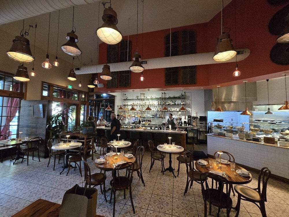 The warm, vintage-style interior of Rosewater Kitchen and Bar, with hanging lights, tiled floors, and an open kitchen.