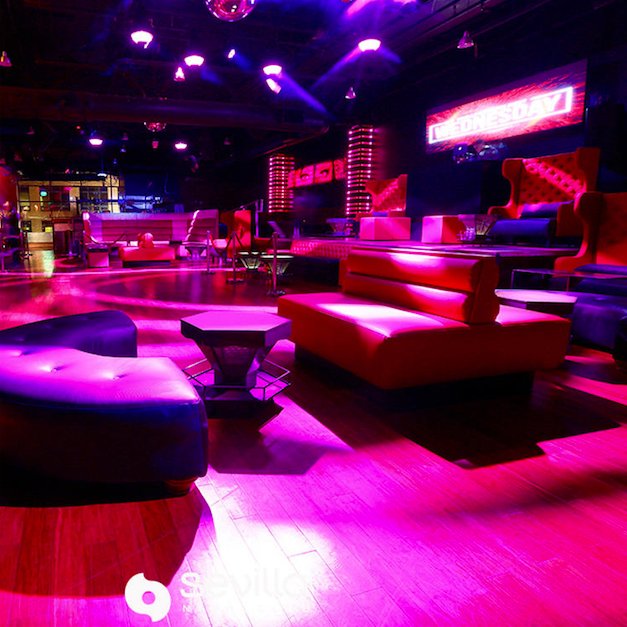 Sevilla Nightclub interior with vibrant pink lighting and modern lounge seating.