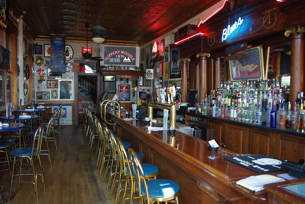 Interior of Slippery Noodle Inn featuring a long wooden bar, bar stools, and walls covered with music memorabilia.
