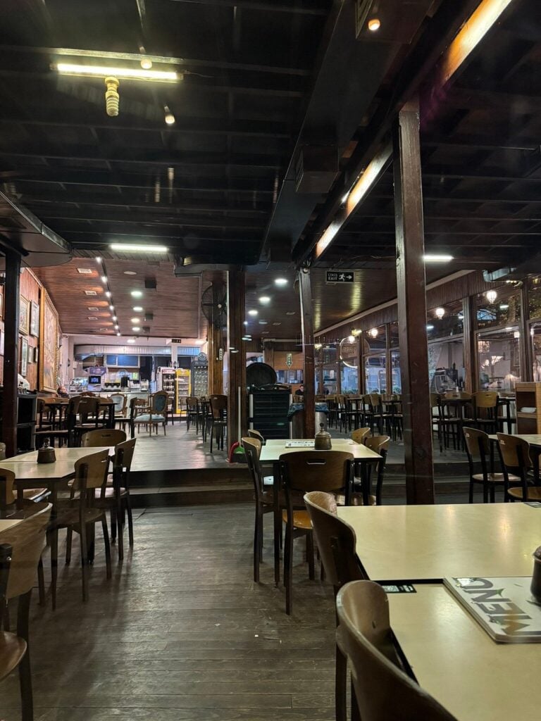 Spacious wooden interior of Tarihi Çınaraltı with neatly arranged tables and warm lighting.
