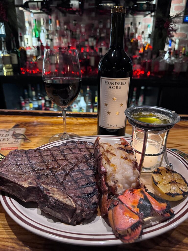 Steak and lobster dinner with wine at the bar inside The Drover.