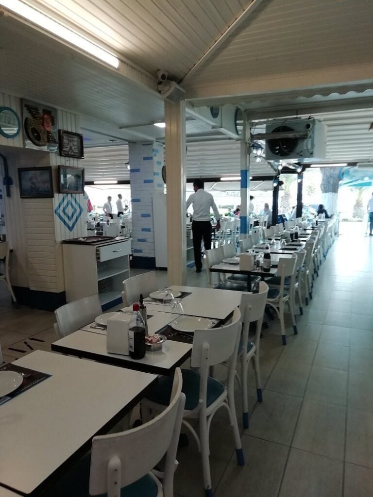 Bright, spacious interior of Tuzla Balıkçısı with rows of white tables.