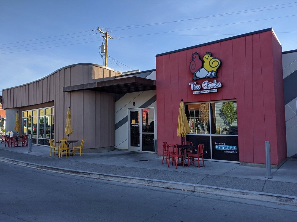 Exterior of Two Chicks breakfast spot with bold signage and colorful outdoor seating.