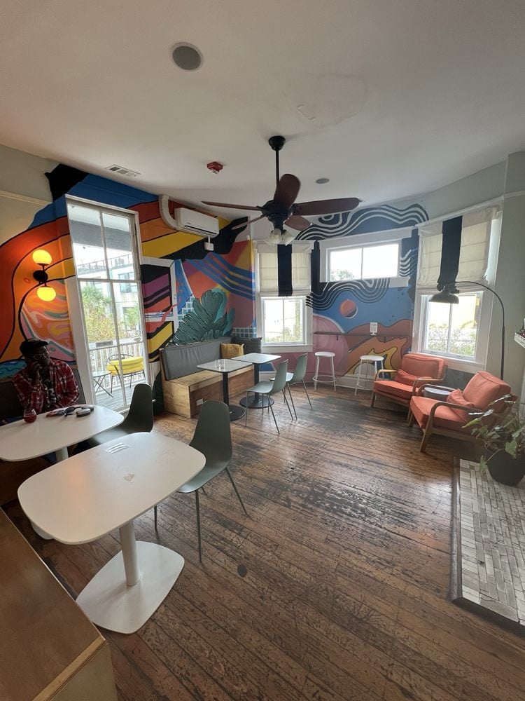 Interior of Two Tides Brewing Company with colorful mural walls, modern furniture, and wooden floors.