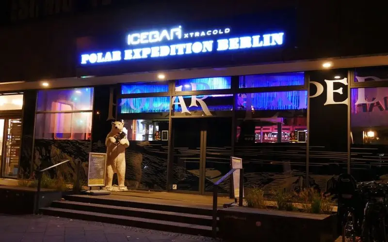 The entrance of Berlin Ice Bar is lit with neon signs and a polar bear figure.