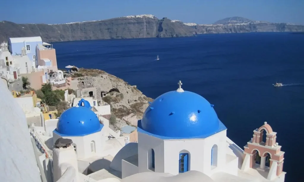 White buildings with blue domes overlook the deep blue sea in Santorini.