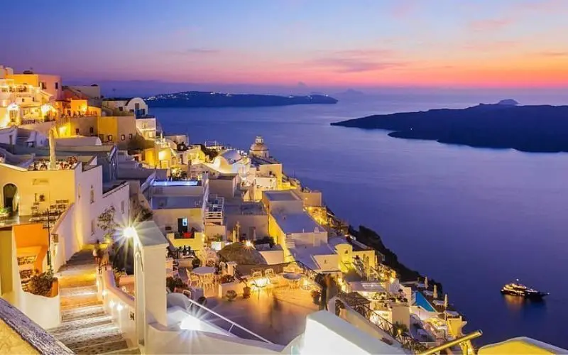 Whitewashed buildings overlook the sea at sunset in Santorini, Greece.
