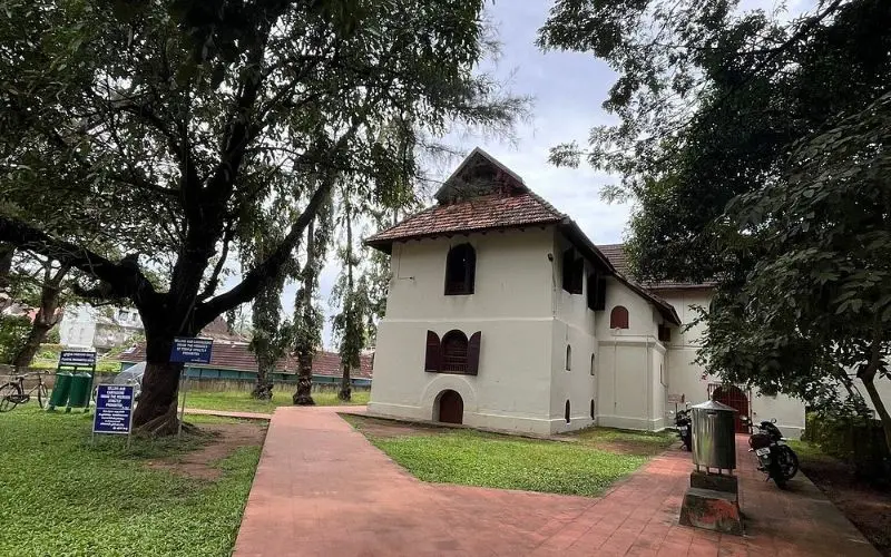 Kochi with a white colonial-era building surrounded by trees.