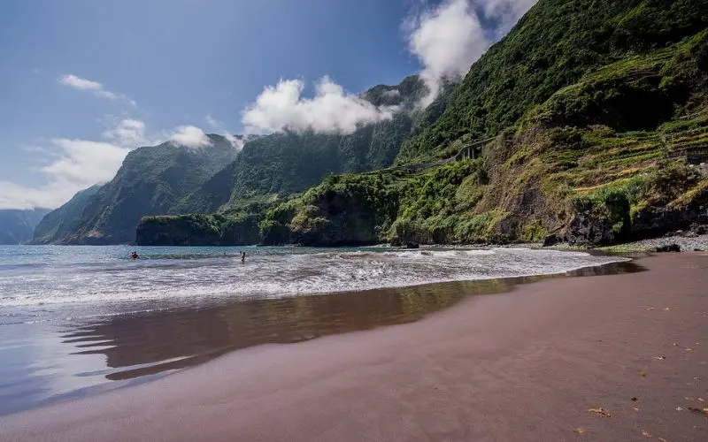 Black sand beach with green cliffs in Madeira.