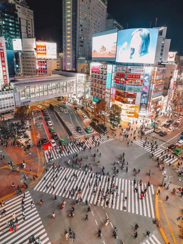 Aerial view of Shibuya Crossing filled with people at night.