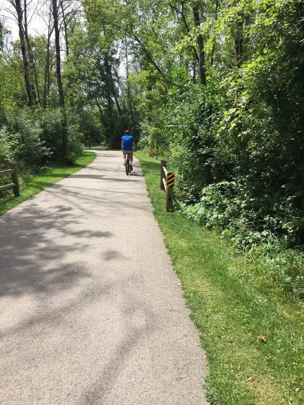 Cyclist riding along a shaded paved trail in Wauwatosa.