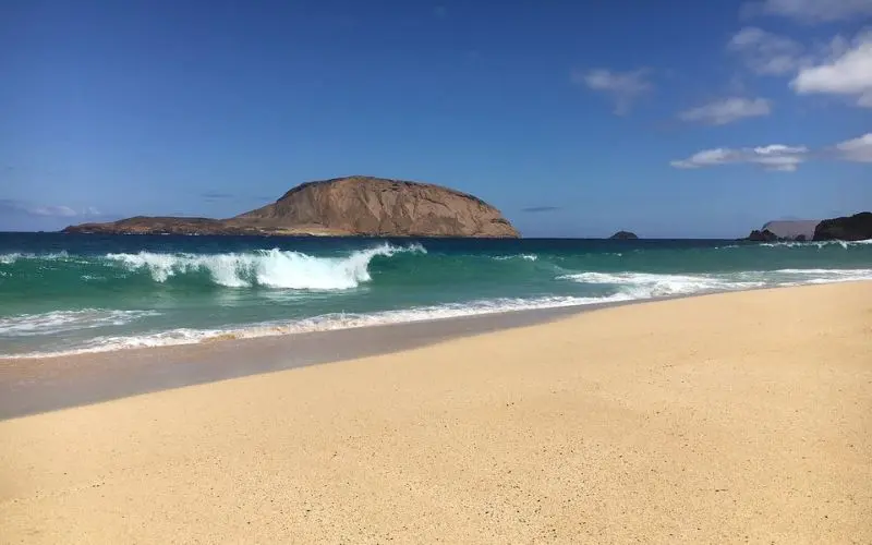 Sandy beach with waves and island view in the Canary Islands.