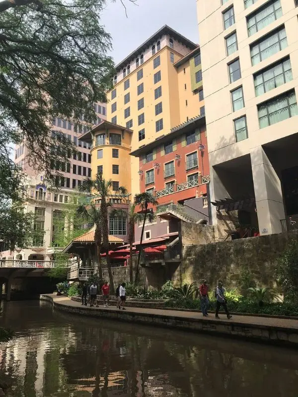 Tall buildings overlook a calm riverside walkway in San Antonio.