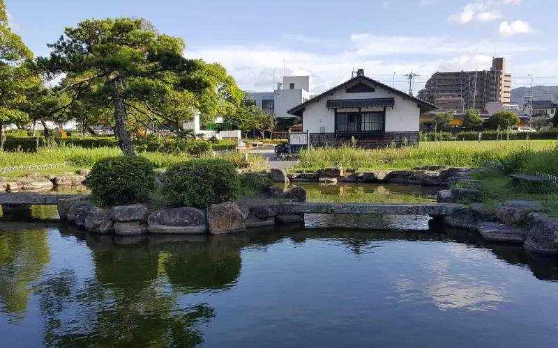 Peaceful pond and garden with a small traditional house in Fukuoka.