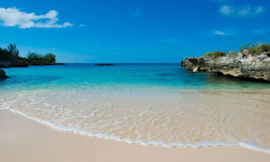 Clear turquoise water gently laps onto a sandy beach in Grand Cayman.