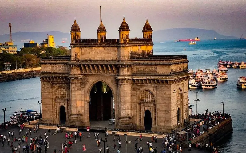 Mumbai with the Gateway of India monument by the waterfront at sunset.