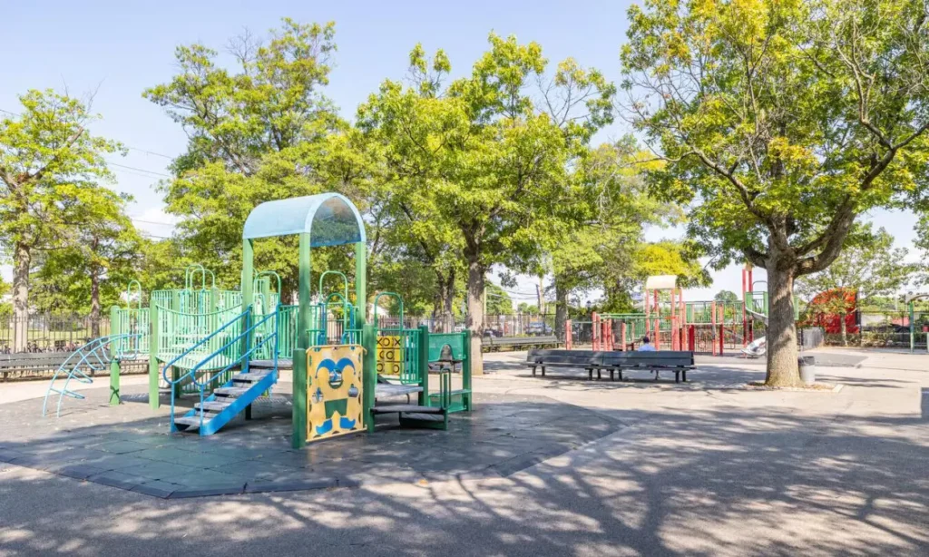 A colorful playground surrounded by trees in Bellerose.