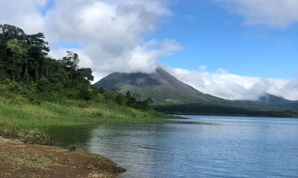 A misty volcano rises beside a lake in lush Costa Rica.