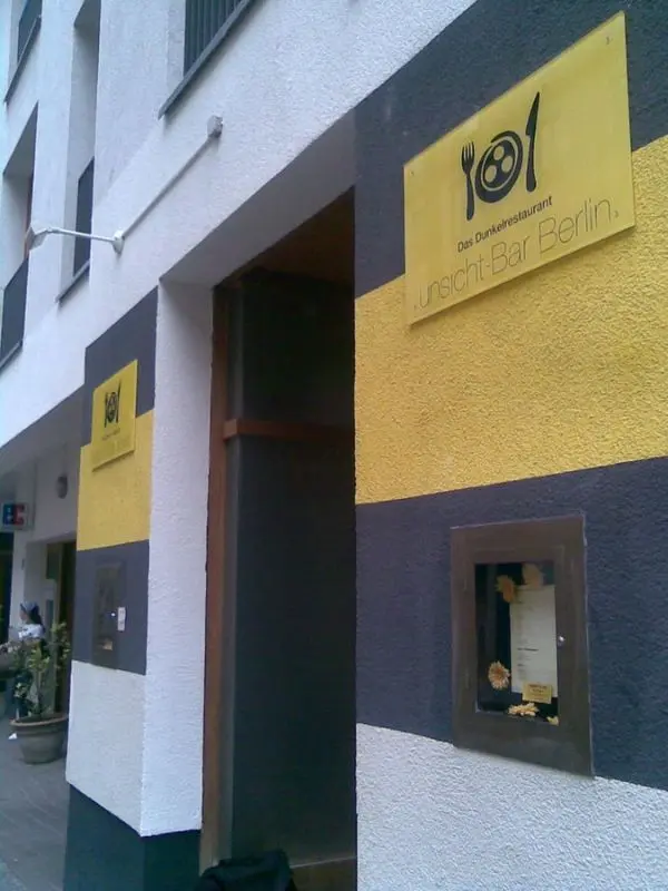 The exterior of Unsicht-Bar restaurant shows its yellow and black sign in Berlin.