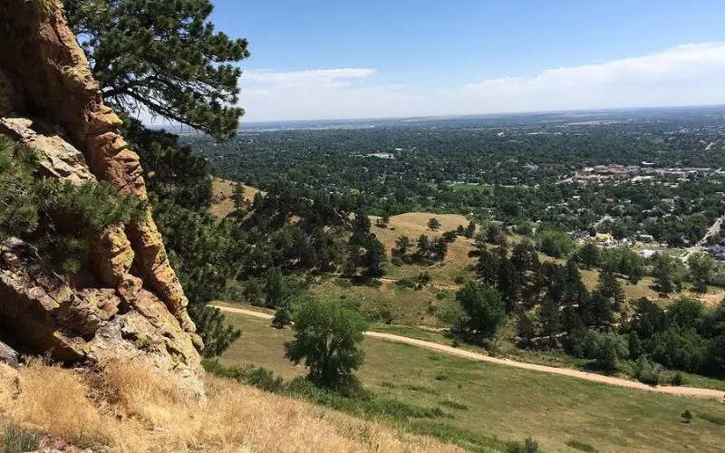Mount Sanitas overlooks a green valley and distant city views.