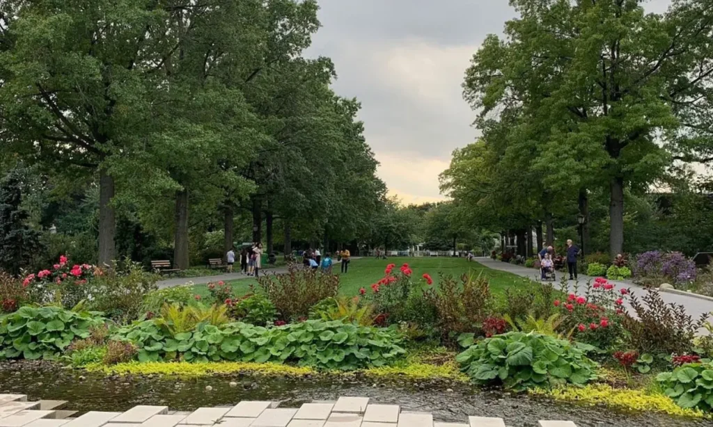 A landscaped garden with flowers, trees, and people walking at Queens Botanical Garden.