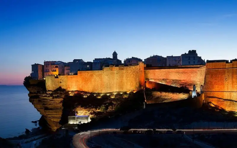 The cliffside citadel of Bonifacio glows at dusk in Corsica.