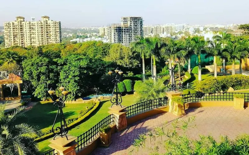 Pune with green gardens and palm trees overlooking city buildings.