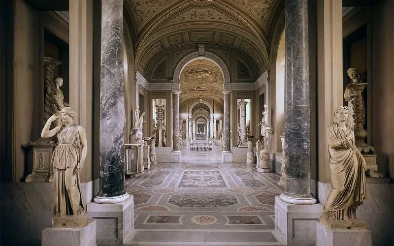 Ornate hallway lined with statues in the Vatican Museums.