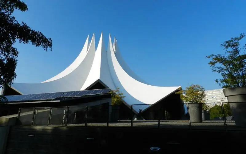 The white tent-like roof of the Liquidrom spa stands out against the blue sky.