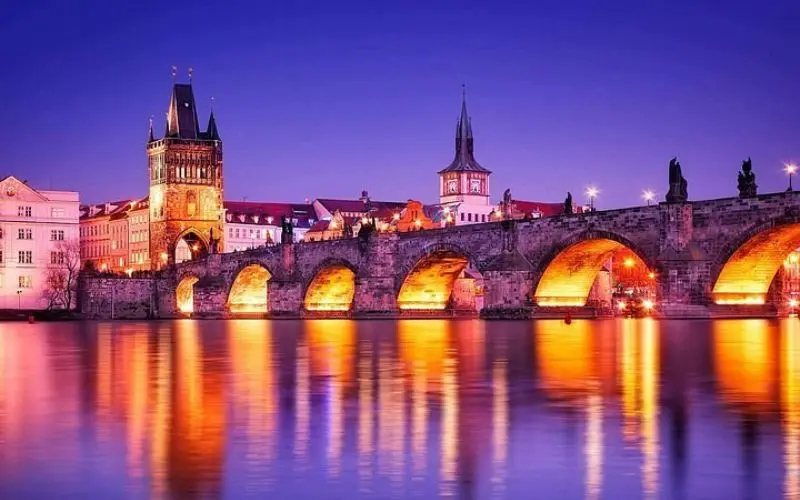 Ahmedabad with the illuminated Charles Bridge reflecting on the river at night.