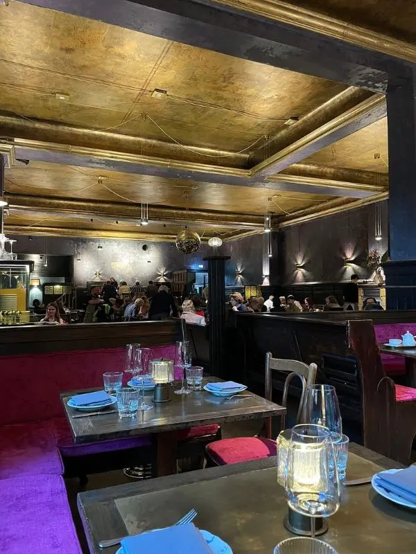 The golden-ceilinged interior of Clärchens Ballhaus is filled with diners.
