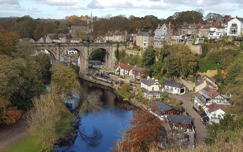 A scenic view of Knaresborough Viaduct over the River Nidd surrounded by houses and trees in Leeds.