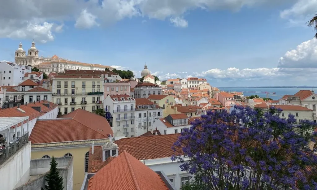 Red rooftops and pastel buildings spread out toward the water in Lisbon.