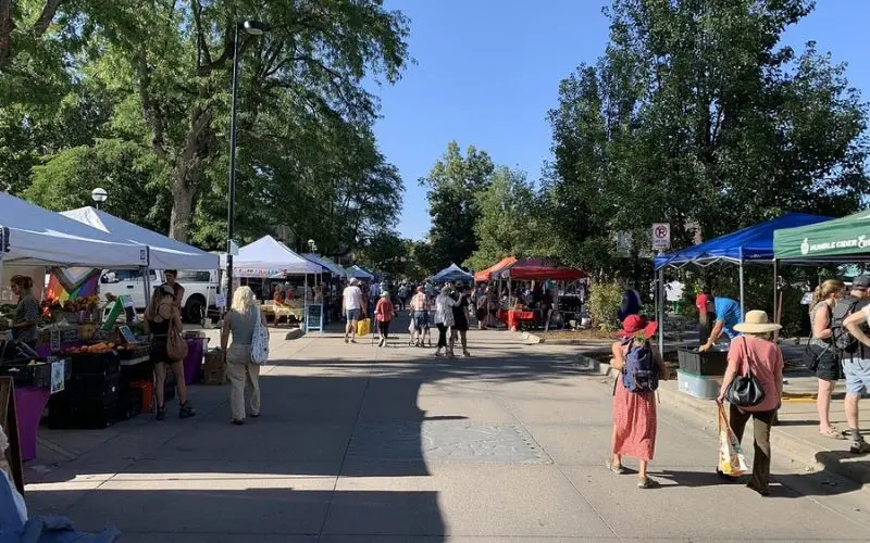 The Boulder Farmers Market has tents and people shopping on a sunny day.