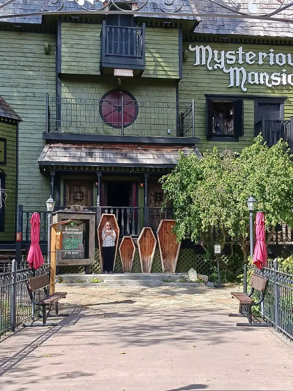 Mysterious Mansion is a haunted house attraction with a spooky green exterior and coffin props.