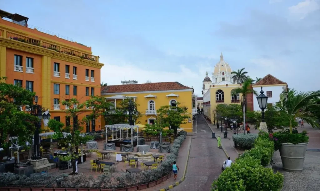 Brightly colored colonial buildings and a church dome line a plaza in Cartagena.